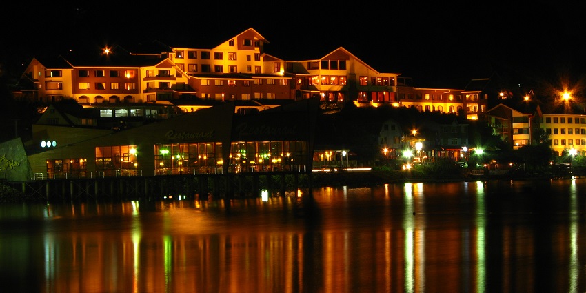 Nighttime view of Puerto Varas, with illuminated buildings reflecting on the calm waters