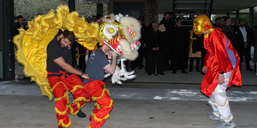 Two men dancing and holding vibrant dragon costumes for a lunar new year festival.
