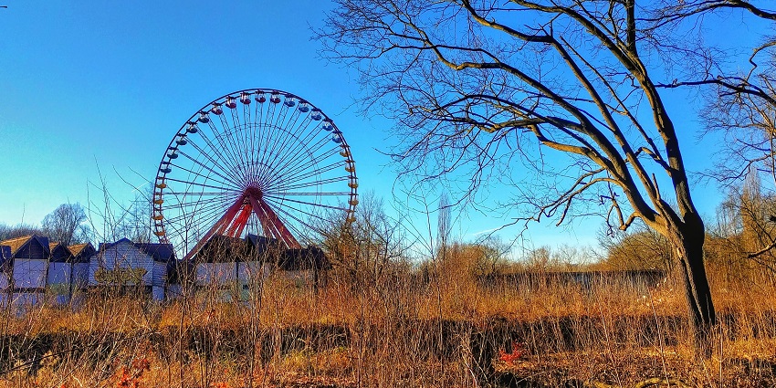 An eerie abandoned amusement park in Berlin with rusting rides and overgrown paths.