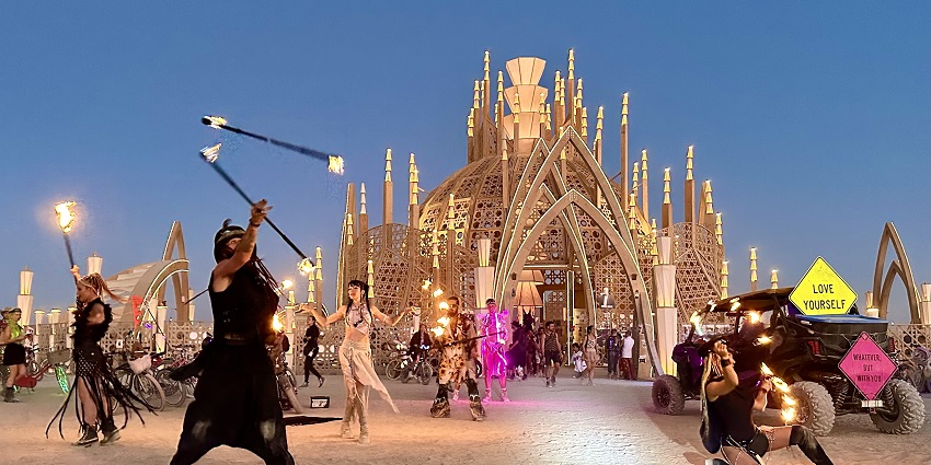 People in costumes performing with fire sticks and dancing in front of the temple structure