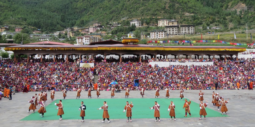 Aerial view of the Thimphu Tsechu festival at Tashichho Dzong, showing a big crowd.