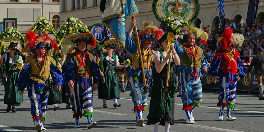 Parade in the Oktoberfest with people holding multiple flags, signages and flowers