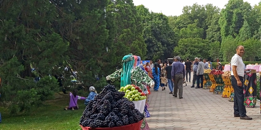 People walking on the pathway with fruits and decorative things on display on both sides