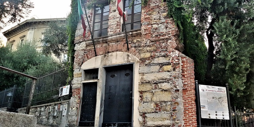 Stone building with historic signage and green plants marks Columbus’s house, a classic thing to do in Genoa.