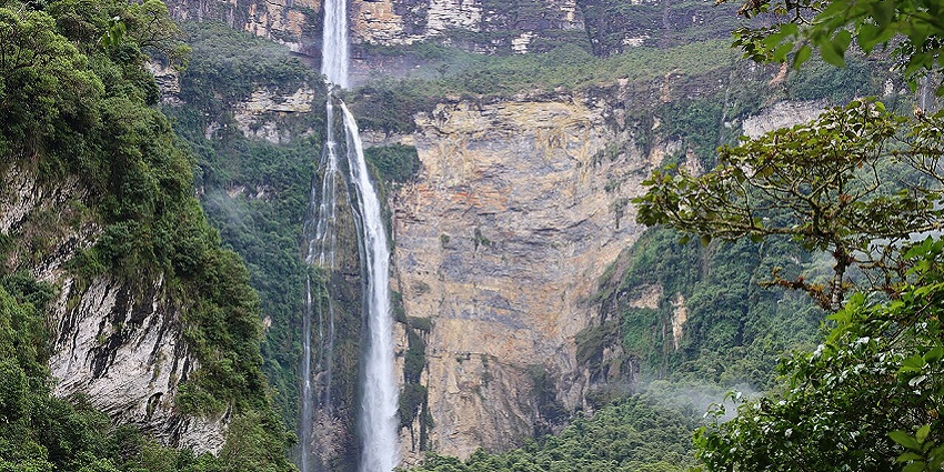 Tres Hermanas Falls is a waterfall flowing on the rocky green surface of a cliff