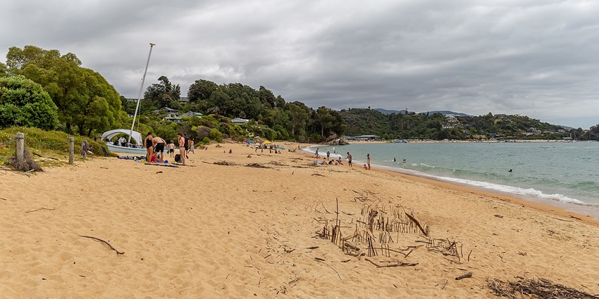 A person paddle boarding on calm waters at Kaiteriteri Beach, showing what to do in Abel Tasman for active visitors.