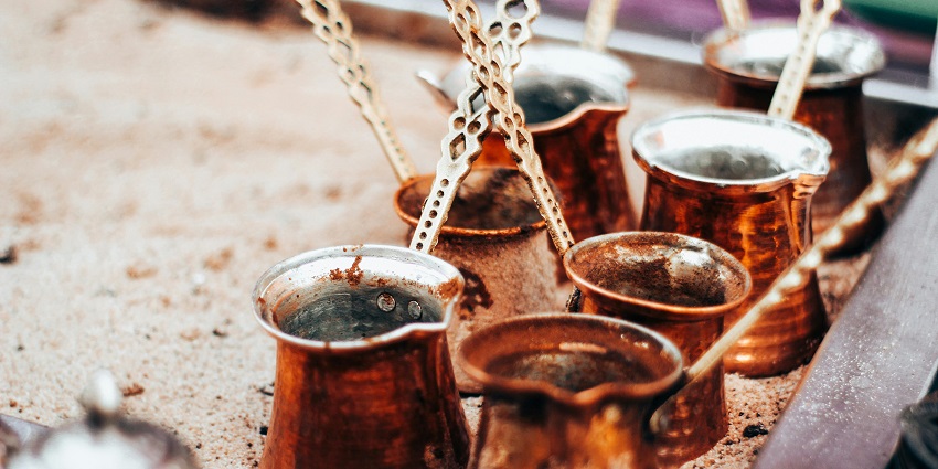 Decorative Turkish coffee sets with engraved copper pots and matching cups on a tray.
