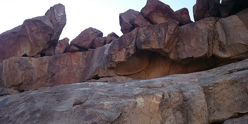 An image of the dark and dramatic entrance to a lava tube, one of the caves in Saudi Arabia.
