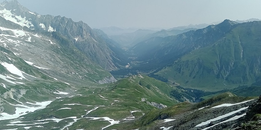 Val Ferret Valley with snow patches partially spread across the green hills and distant fog