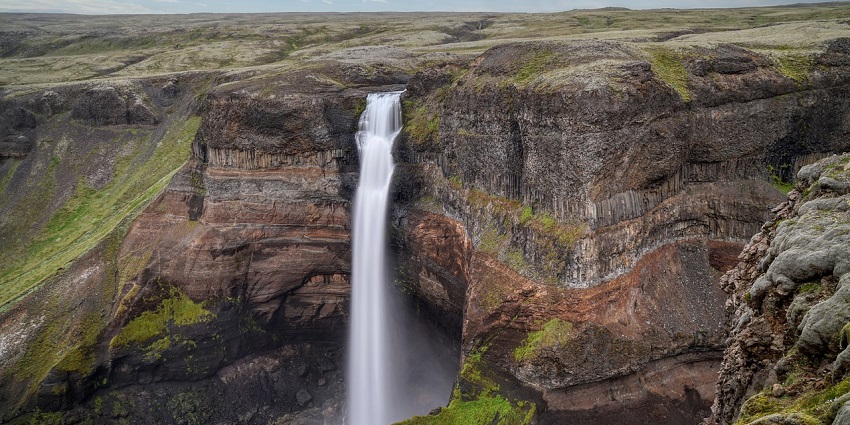 Dettifoss Waterfall is thundering over a cliff while mist is spreading across the canyon.