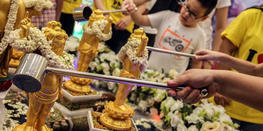 People pour water over Buddha statues in a sacred ritual to celebrate Vesak Day, one of the festivals in Singapore.