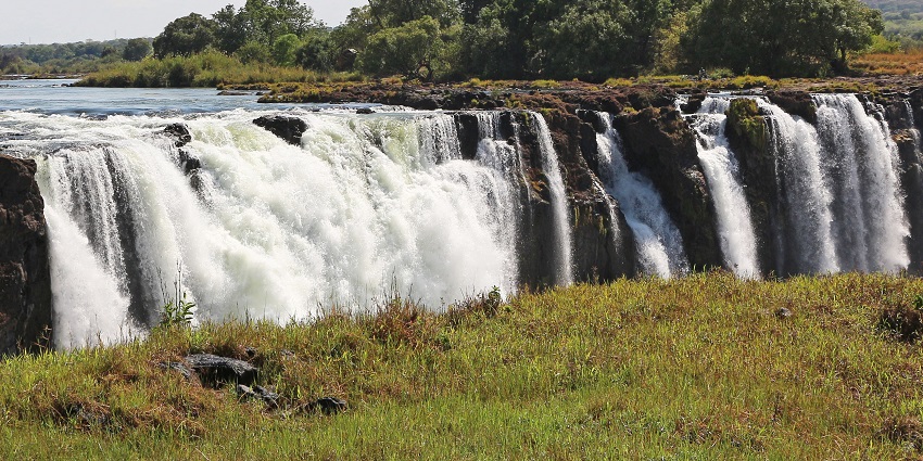 An image of the Victoria Falls cascades over rocky cliffs, one of the most majestic waterfalls in Zambia.