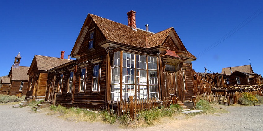 Bodie ghost town's weathered wooden buildings under a clear blue sky during the golden hour