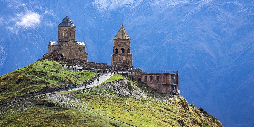 Gergeti Trinity Church on a mountain slope with cloudy sky, one of the best things to do in Kazbegi.