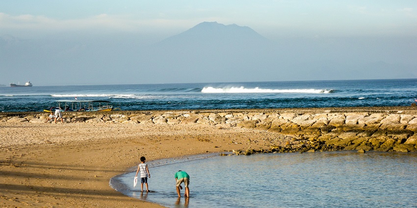 A tourist strolling along Nusa Dua Beach, a peaceful activity in Tanjung Benoa