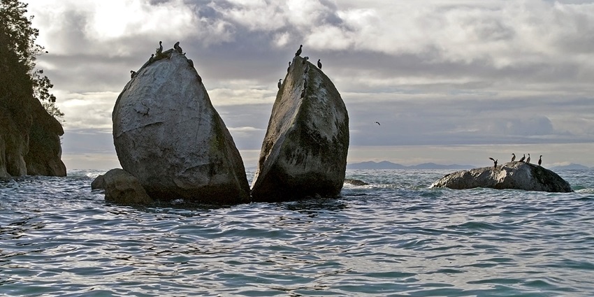 Image of the round boulder split in two in the ocean,one of the top things to do in Abel Tasman.