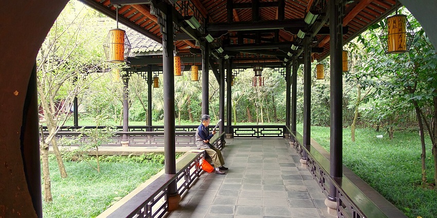 A man exploring the corridor of a Thatched Cottage, an exciting thing to do in Sichuan.