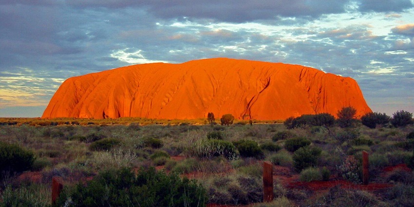 The sun rising over Uluru with glowing red rocks, one of the top things to do in Australia in March.