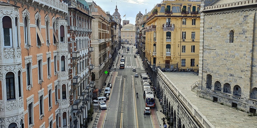Wide street with arched walkways and classic buildings along Via XX Settembre, a scenic thing to do in Genoa.