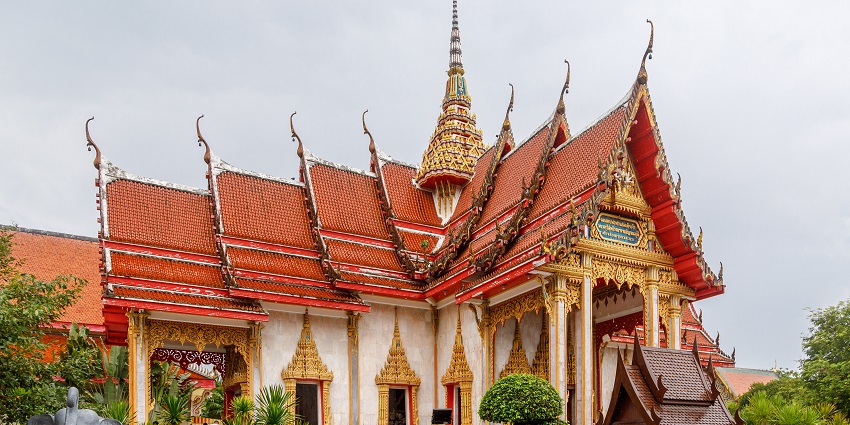 Ornate temple structure of Wat Chalong in Phuket with golden details and pagoda.
