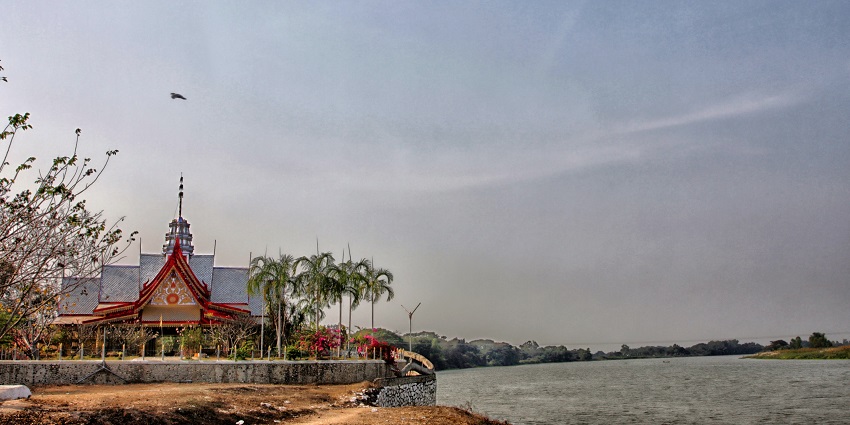 Wat Khlong Thom temple features traditional Thai architecture with golden ornaments and a peaceful courtyard surrounded by tropical greenery.