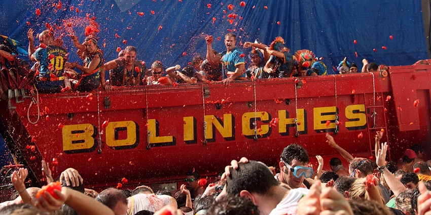 People throwing tomatoes at each other from a big red structure at the people standing below