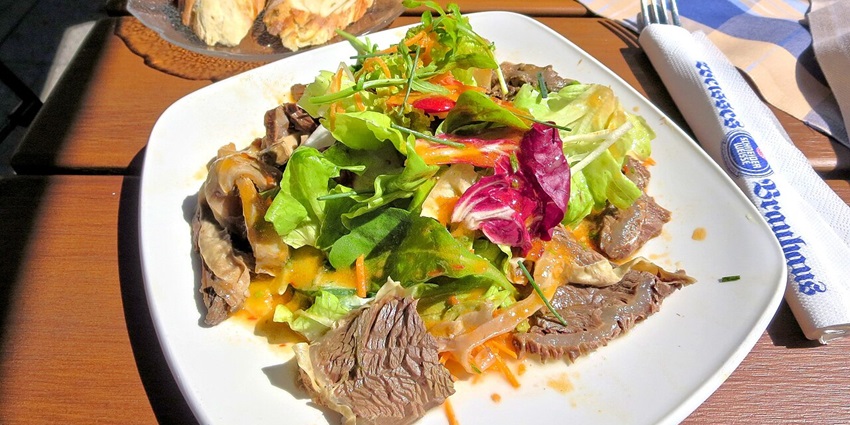 Calf's head dish in Munich with different green veggies and bread served on a white plate
