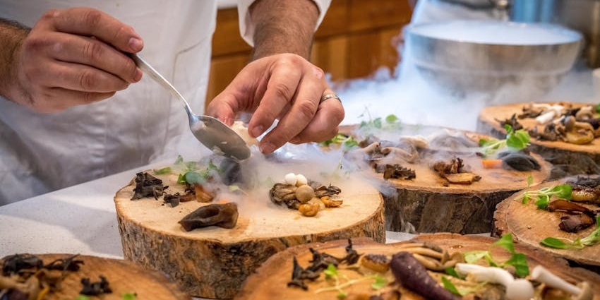A chef carefully plates the delicious food on a plate like a tree with green garnishing