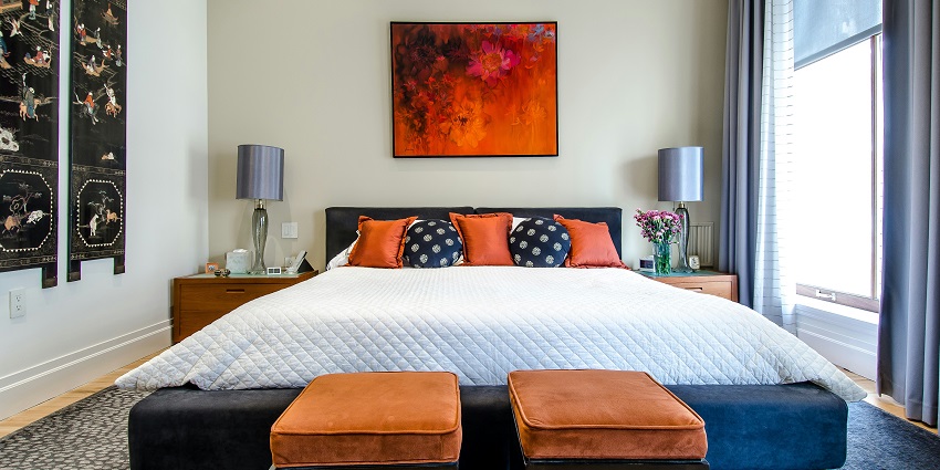 A minimalist bedroom, featuring a neatly made bed centered between two large windows