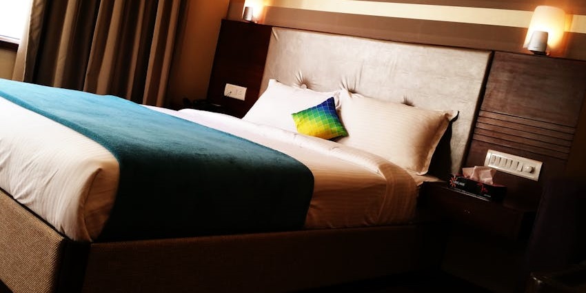 Modern hotel room with a neatly made bed, furniture, and ambient lighting.