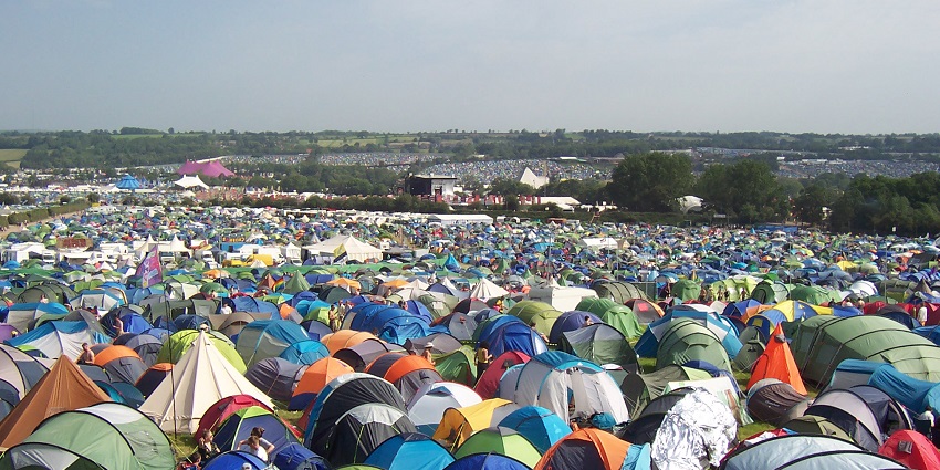 Glastonbury Festival camping site with a lot of vibrant camping tents and people standing