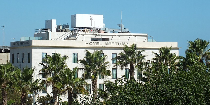 Building of the Hotel Neptuno behind the tall palm trees at a distance in Valencia