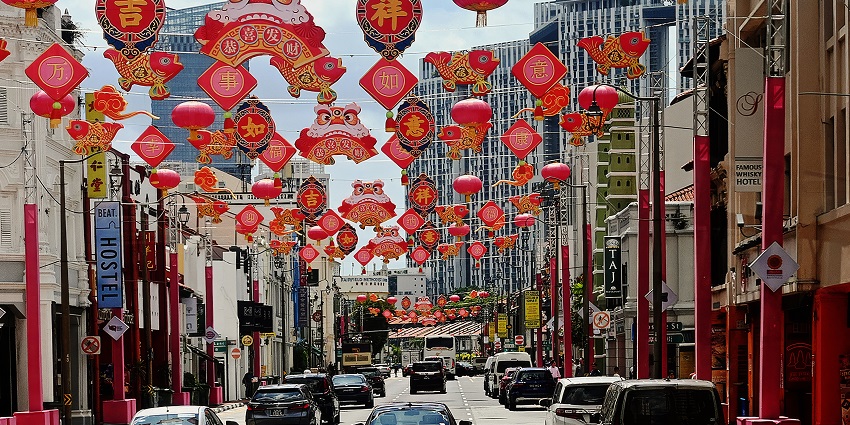 A busy road is decked with traditional Chinese lanterns and other props as cars move below