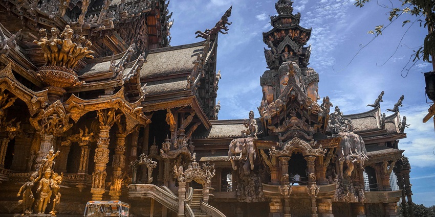 Teakwood carvings of elephants and traditional Thai figures lined up at a local crafts display.