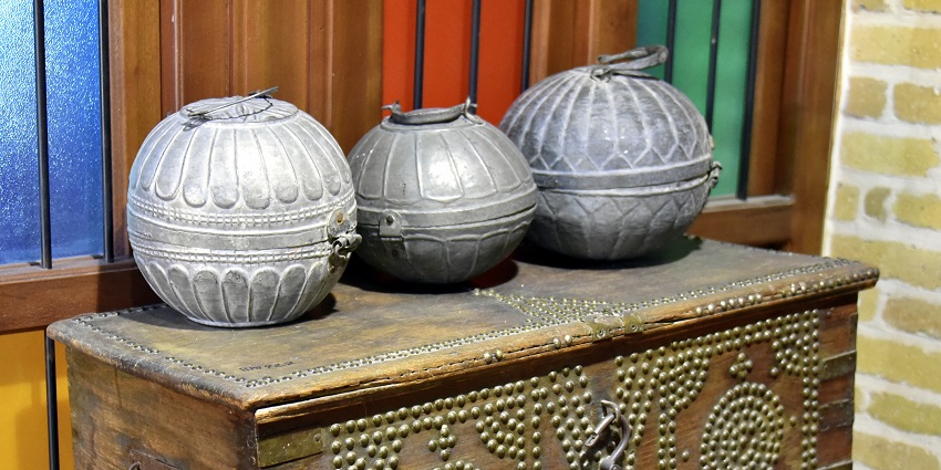 Intricately carved wooden chest with metal studs, placed inside a museum or exhibition room.