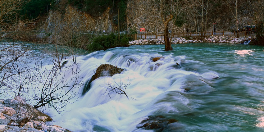 Yerkopru waterfall flows into the pool from small green cliffs covered in moss and plants.