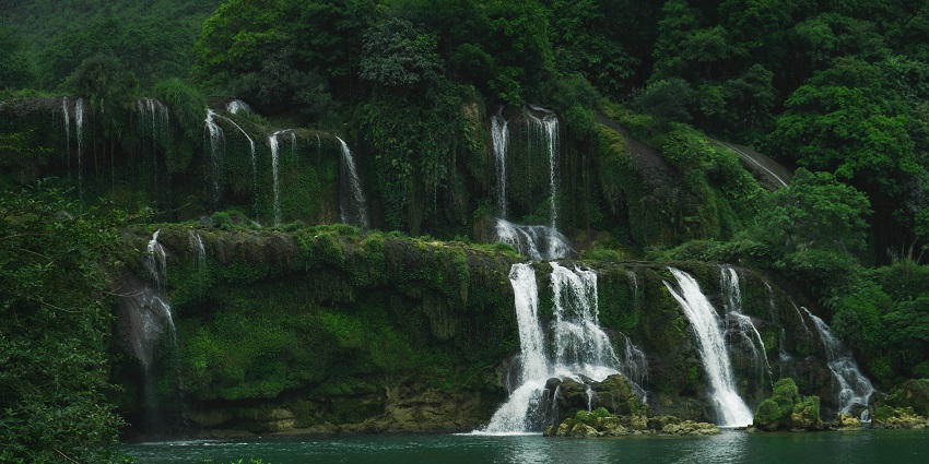 Massive man-made waterfall with city skyline and visitors enjoying the scenic view.