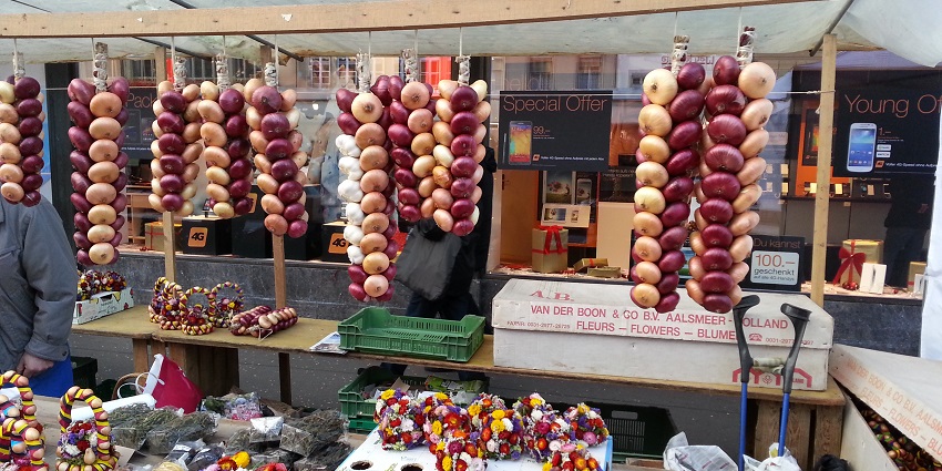 Colorful onion and garlic braids on display at an outdoor market stall during a festival.