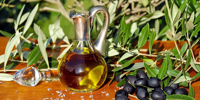 An image of bottled Spanish olive oil placed on a rustic wooden table with olives.