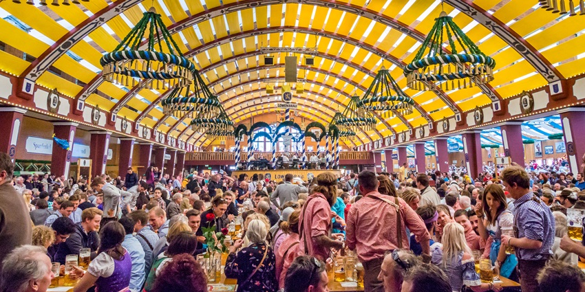 Parade in Oktoberfest with a cart full of barrels and women on the cart drinking beer