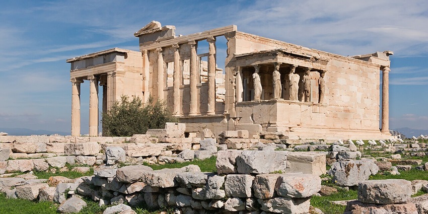 The Erechtheion temple of ancient Greece, with Caryatid columns, ruins, and blue sky in Athens.