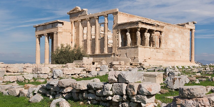 The Acropolis of Athens with the Parthenon on a rocky hill above the city and greenery, one of the top historical Places in Athens Greece.