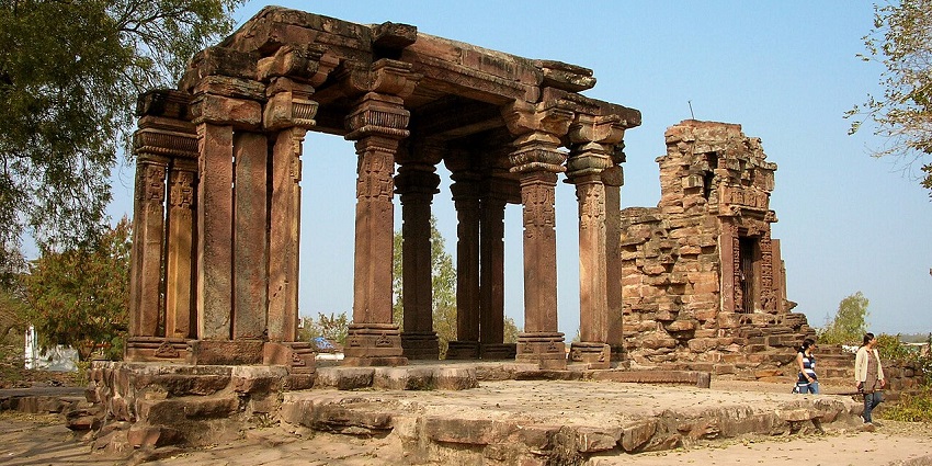 Devi temple with an old ruined architecture, pillars, broken walls and people visiting.