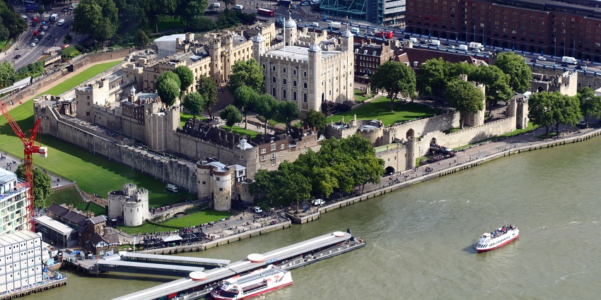Tower of London from above with multiple boats, vehicles on the highway and greenery