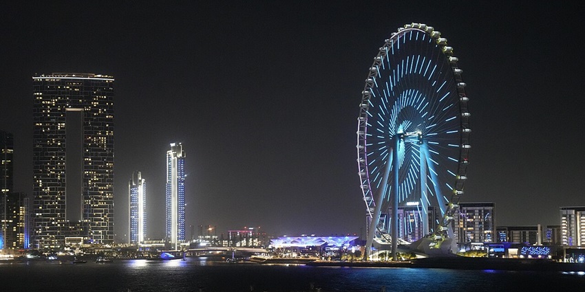 Ain Dubai Ferris wheel illuminated with blue lights during a vibrant night show.