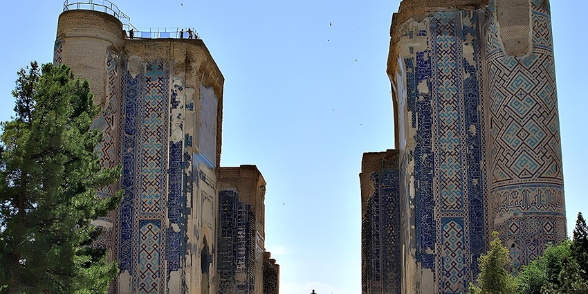Ak Saray Palace with old ruined architecture, a distant statue and people exploring the palace