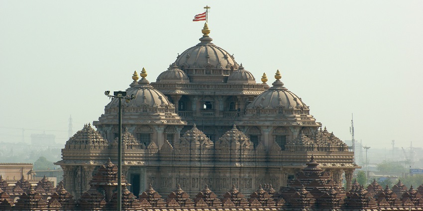 Intricately carved complex of the Akshardham Temple with a wide-angle view under a clear sky.