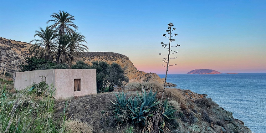 Anafi island in Cyclades with rocky cliffs and distant Greek architectural buildings.