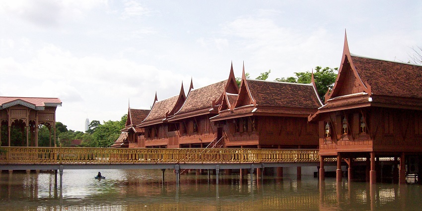 Ornate white temple with dark tiered roof and intricate carvings, set against blue sky, one of the best historical places in Thailand.