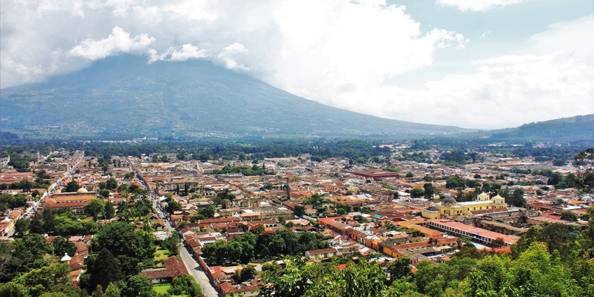 Colourful colonial street in Antigua with Volcán de Agua in the background.